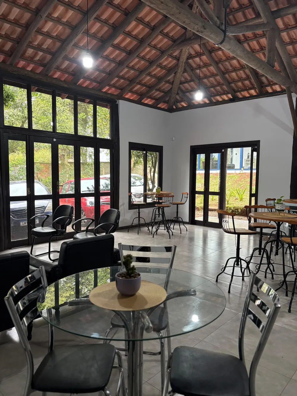 Espaço de café com mesas redondas e telhado aparente