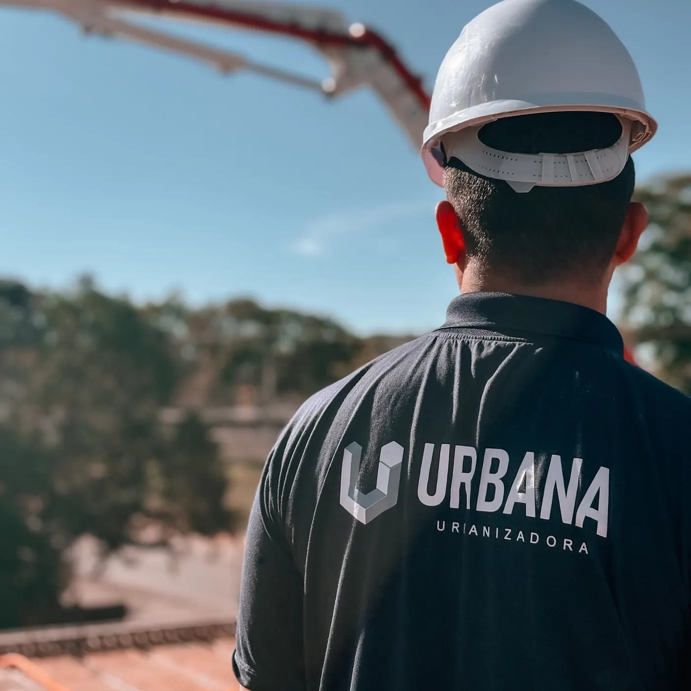 Profissional da Urbana de capacete branco e camiseta com a marca, observando a obra