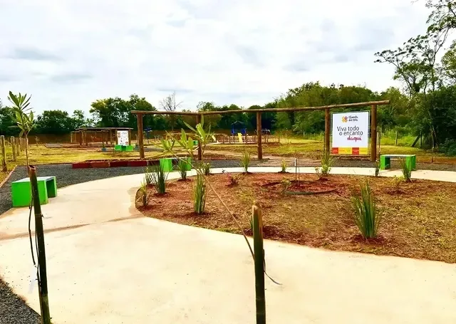 Caminho calçado com bancos e a placa do loteamento
